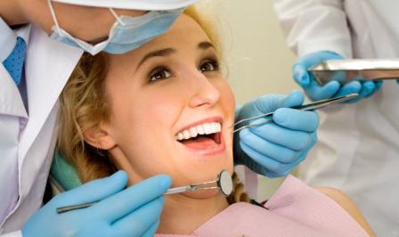 Image of young lady with dentist over her before checking oral cavity